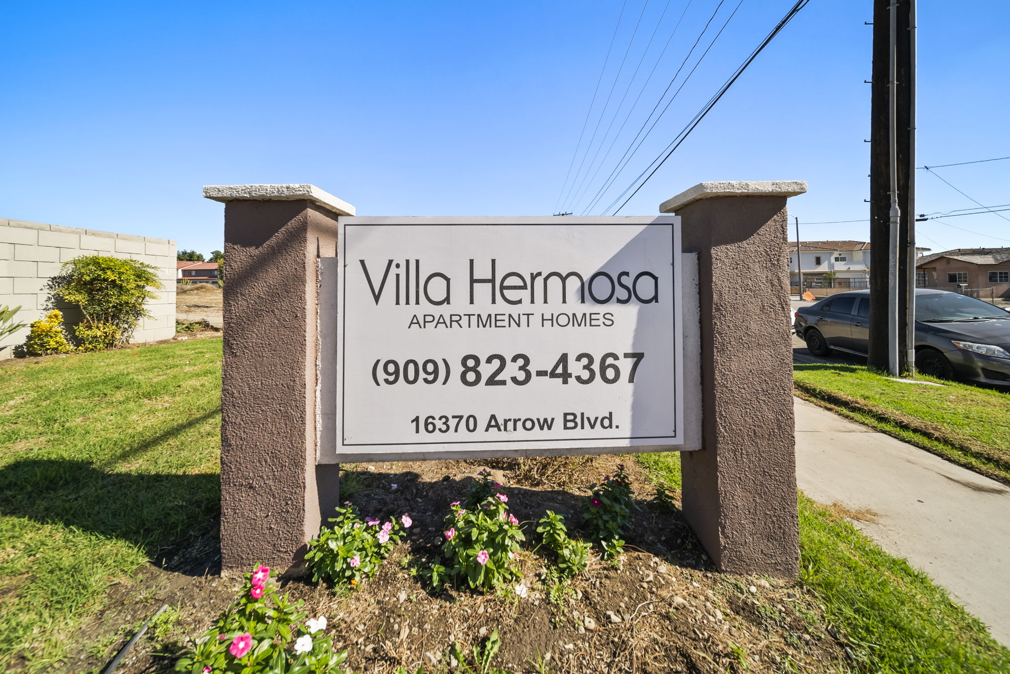 A sign for Villa Hermosa Apartment Homes with a phone number and address.
